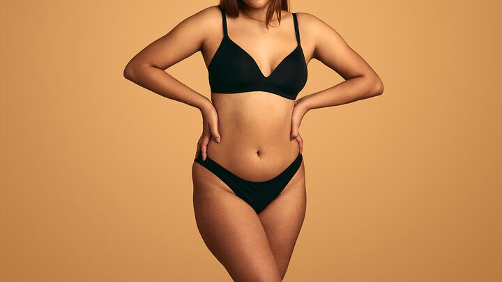 How to take care of the skin on your body? Beautiful curvy woman's body in black underwear, arms on hips