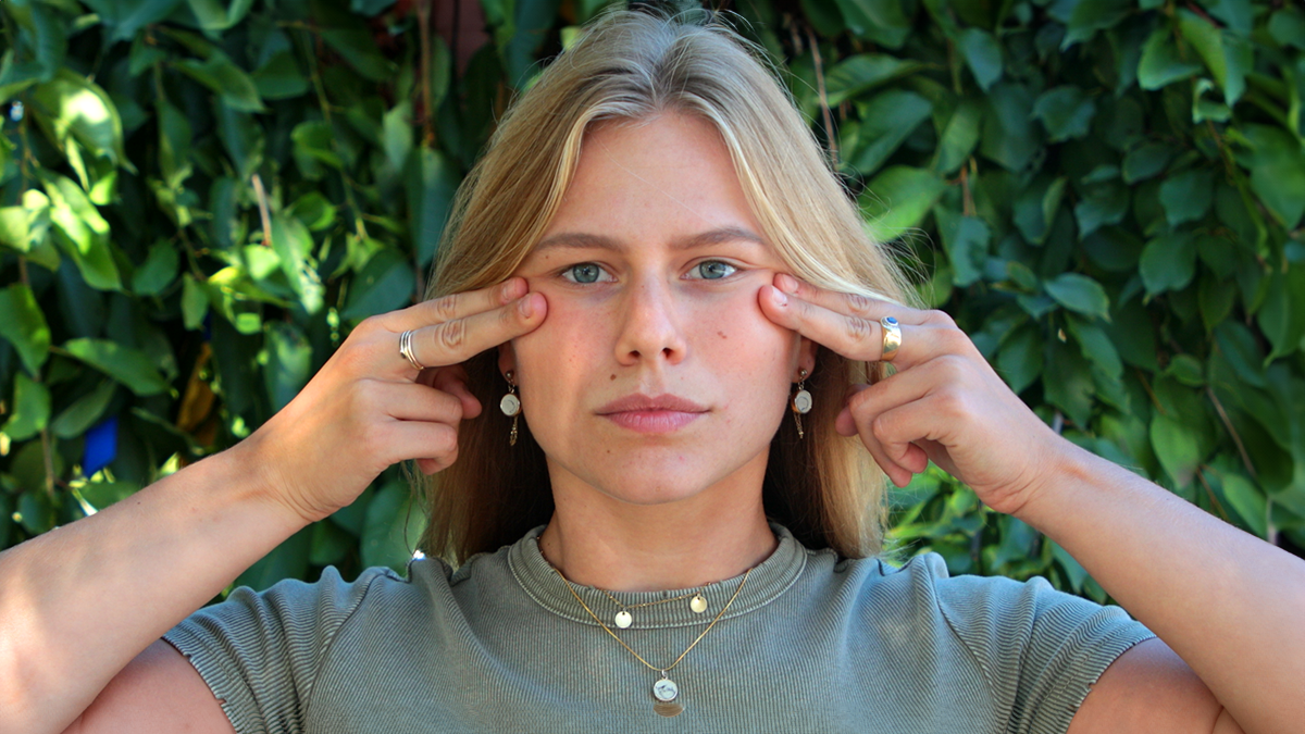 Five face yoga methods for a fresher, plumper face A model doing face yoga with fingertips on her cheekbones